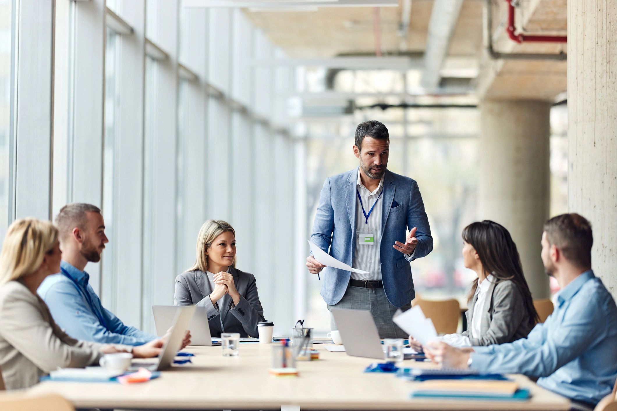 Leader presenting policy review plan to a team in an office meeting