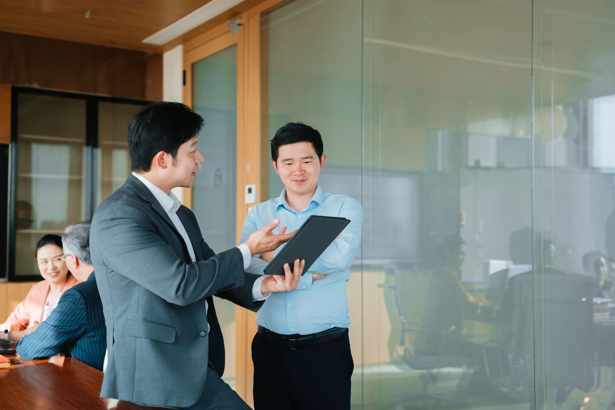 Professionals collaborating in a conference room reviewing information on a tablet